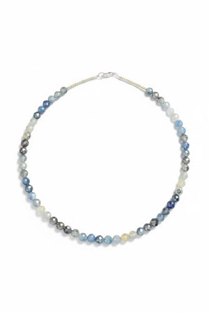 The ANN LIGHTFOOT Variegated Sapphire Ras Du Cou Necklace 18″ features round, faceted beads in shades of blue, gray, white, and yellow arranged in a subtle gradient and is secured with a silver lobster clasp.