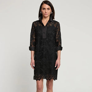 A person stands against a plain background wearing the Aileen Black Lace Dress by Hinson Wu, featuring knee-length black lace with 3/4 sleeves and button details. Paired elegantly with black high-heeled sandals, this outfit exudes a formal style perfect for the holiday season.