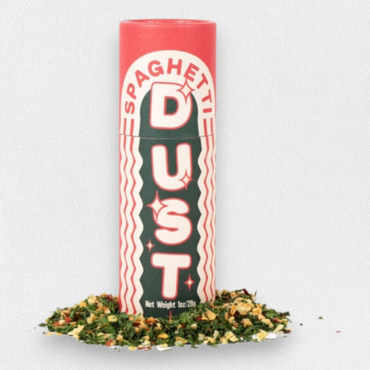 A cylindrical spice container labeled &quot;L&#39;ISOLINA PASTA - SPAGHETTI DUST&quot; stands upright on a white background. The container features a red cap, green body, and white text accented with decorative red lines. At its base, loose dried herbs and spices evocative of Aglio Olio e Peperoncino are scattered around.
