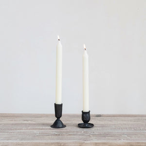 The CREATIVE COOP HAND-FORGED CAST IRON TAPER HOLDER in black features a hammered texture, wide flared base, and slender cylindrical top—ideal for industrial decor and shown upright against a plain white background.