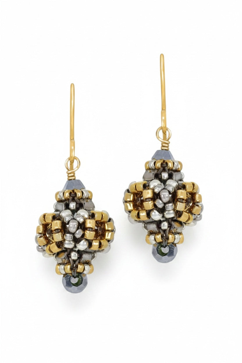 These elegant MIGUEL ASES - CRYSTAL MIYUKI PYRITE EARRINGS by MIGUEL ASES, INC. showcase intricate beadwork with Miyuki seed beads in gold, silver, and black hues, decorative patterns, gold hooks, and a small black bead at the bottom for a refined touch.