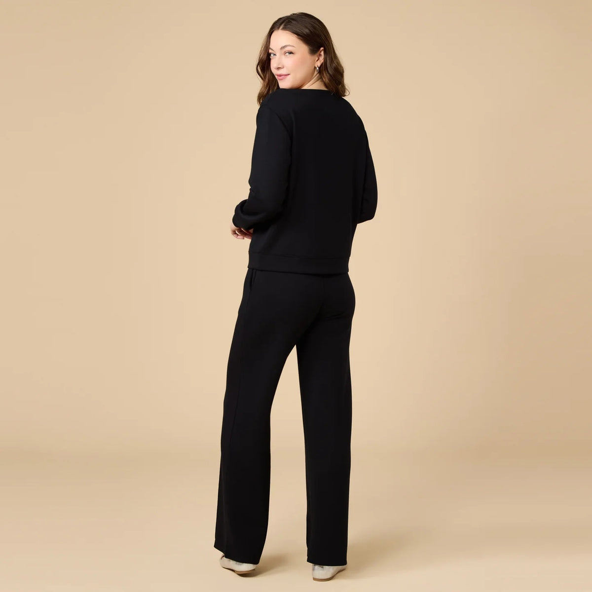 A woman wears a SOFTIES - DREAMTECH BOAT NECK WITH PINTUCK PANT SET in olive green, featuring a long-sleeve boat neck top and matching wide-leg pintuck pants.