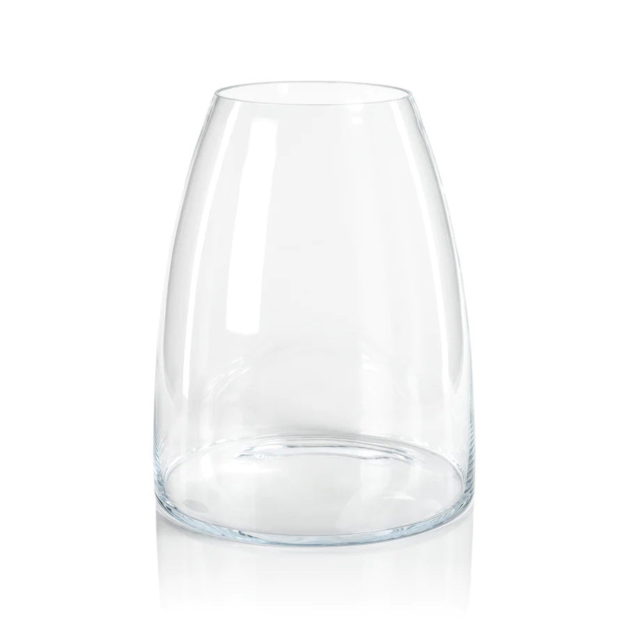 The KOBAYASHI GLASS VASE by ZODAX is a clear, slightly tapered, cylindrical glass vase with a rounded bottom and smooth surface. It reflects light beautifully and features no decorations or engravings. The vase stands upright on a white, reflective surface. For this item, INSTORE PICKUP ONLY; please check the product dimensions before purchasing.