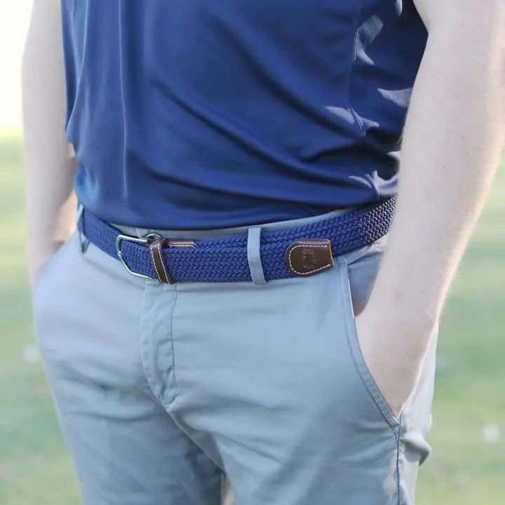 The ROOSTAS - PEEBLE BEACH WOVEN STRETCH BELT by ROOSTAS features a navy braided design with brown leather ends and a silver adjustable clasp, shown coiled on a white background.
