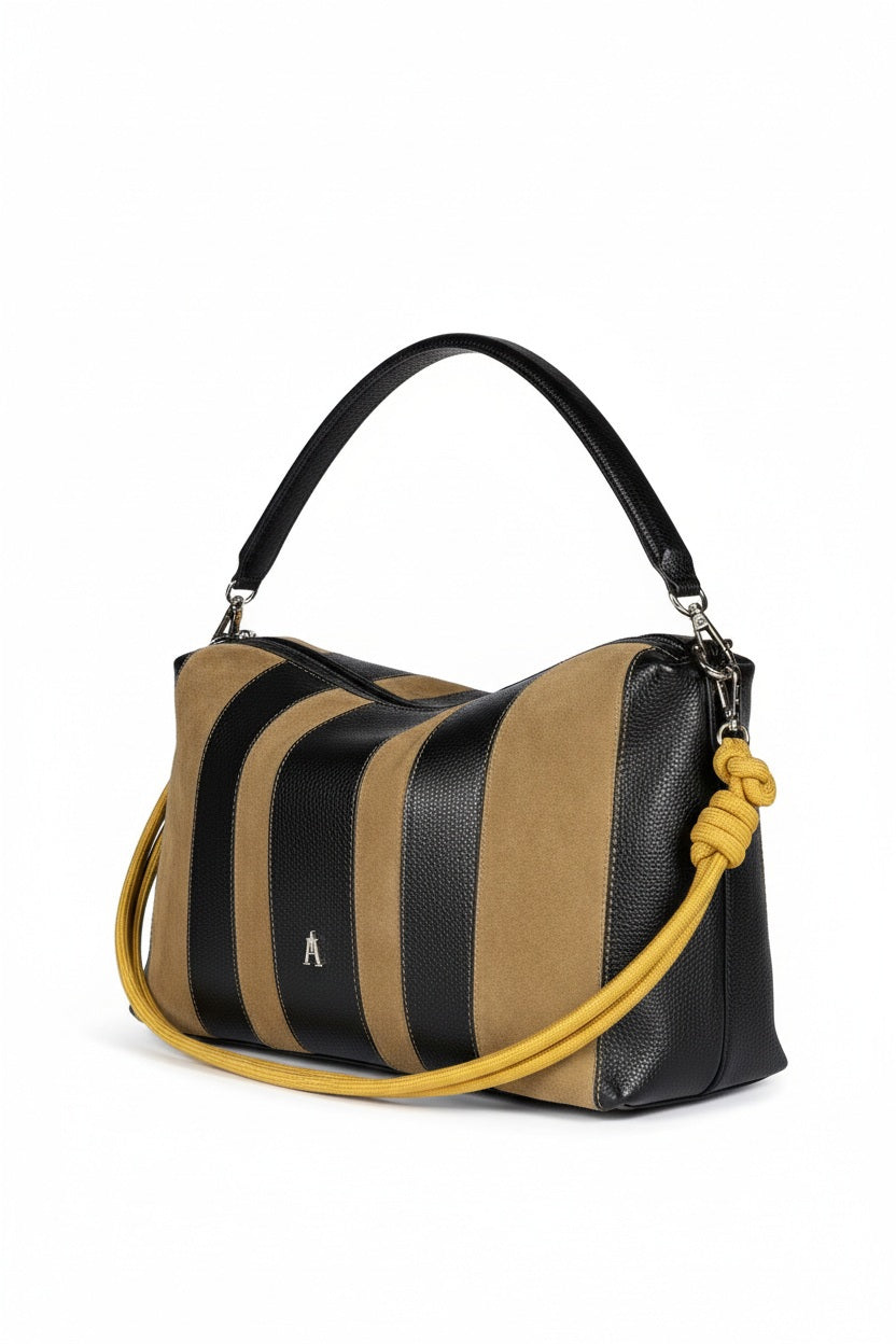 The CRAIE STUDIO HALO STRIPE NOIR SEPIA handbag features black and tan vertical stripes, a black handle, a yellow knotted shoulder strap, and a subtle silver logo on the front. Expertly crafted from grained leather by CRAIE STUDIO, this bag showcases a modern, structured silhouette that enhances its sophisticated allure.