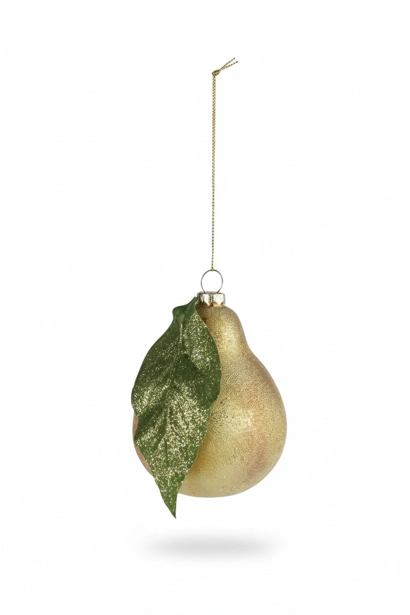 A HAND PAINTED GLASS PEAR ORNAMENT WITH GLITTER shaped like a pear with a glittery green leaf, hanging from a gold cord with a gold glitter finish.