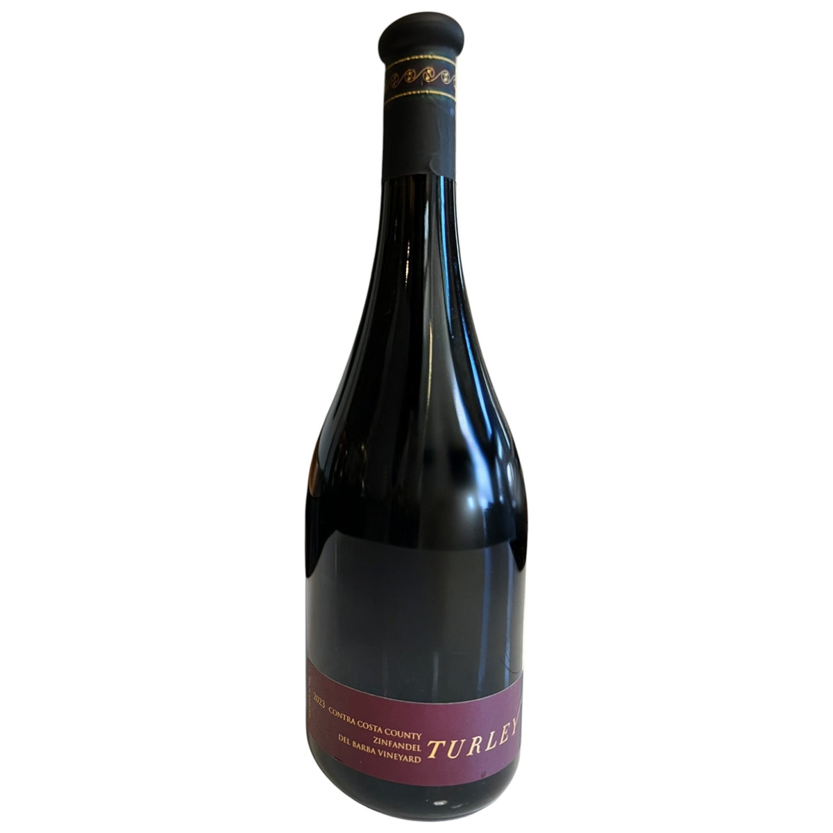 A dark glass wine bottle with a long neck and a black capsule on top features a black and maroon label reading “TURLEY.” Crafted by WINE: ADVINTAGE, this distinctive bottle contains their TURLEY ‘DEL BARBA’ ZINFANDEL 2023, renowned for its rich character and celebrated old vine heritage.