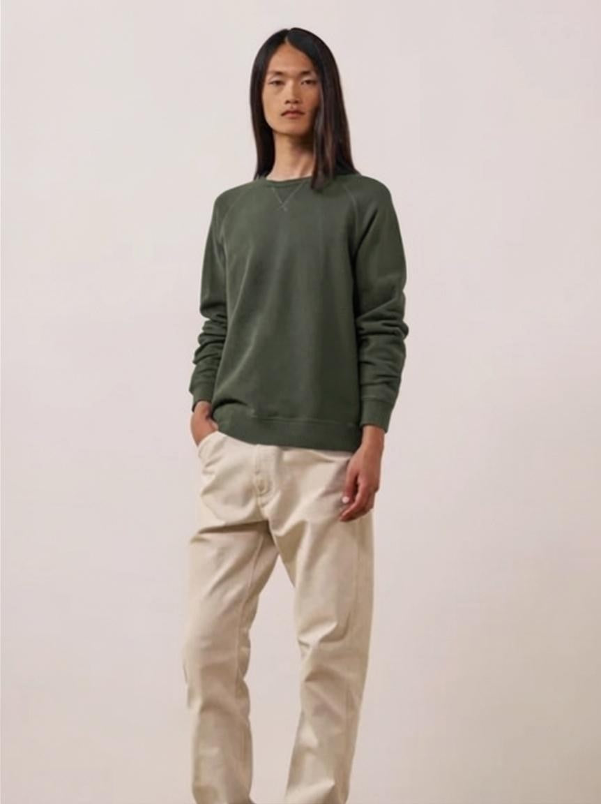 A person with long straight brown hair wears the HARTFORD - LIGHT FLEECE SWEATSHIRT IN ZINC, looking directly at the camera with a neutral expression against a plain light background.