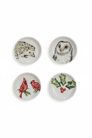 Six small, round Creative Coop stoneware dishes with hand-painted botanical animal illustrations of a hedgehog, owl, birds, or winter greenery.