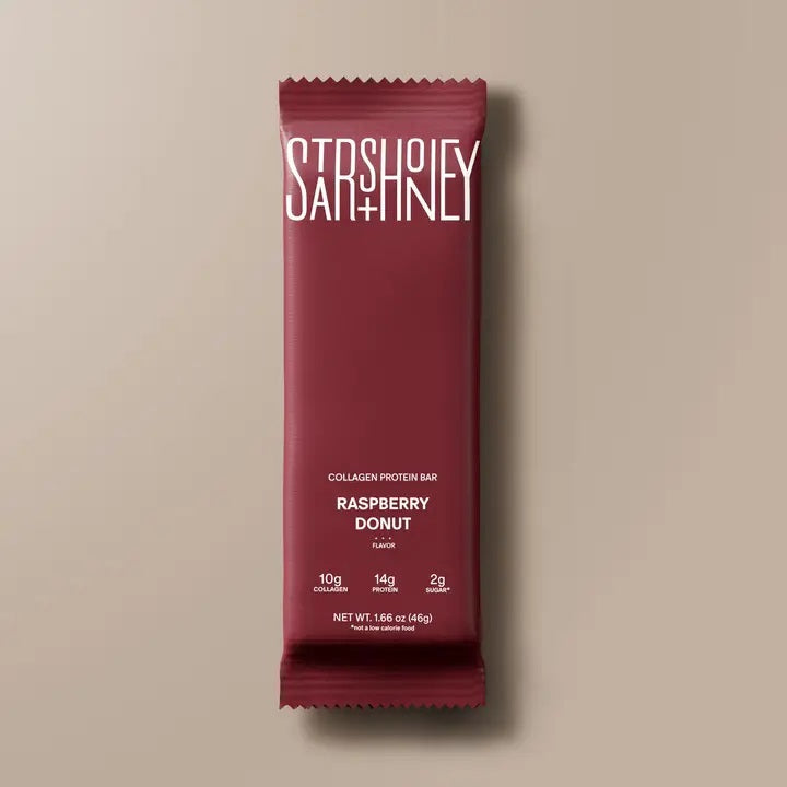 A maroon STARS+HONEY - RASPBERRY DONUT protein bar is shown. This raspberry donut-flavored bar from STARS+HONEY highlights 10g collagen, 14g protein, and only 2g sugar per bar on the front of the package—making it a perfect healthy snack.