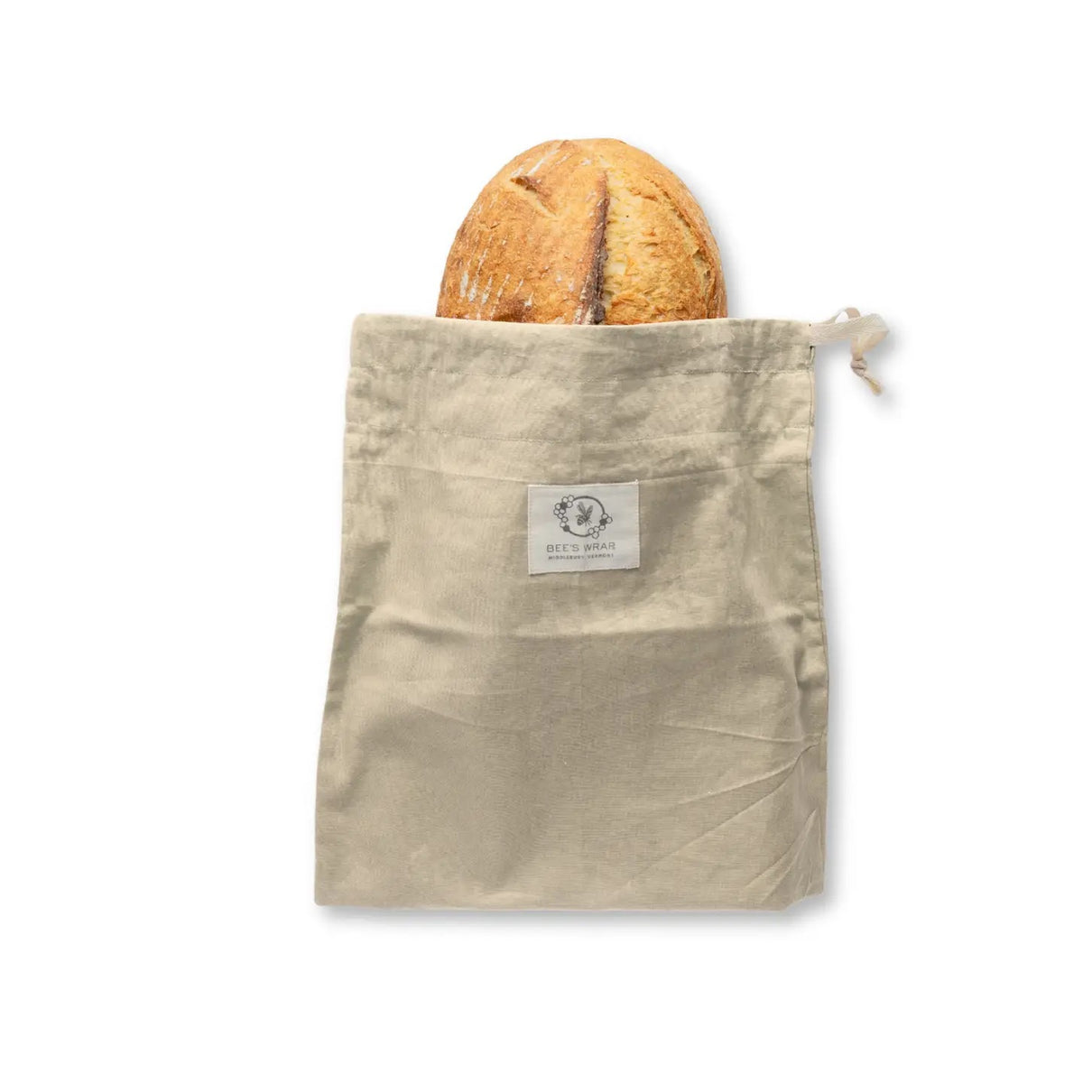 A round loaf of bread is partially tucked inside the BEES WRAP - BEESWAX REUSABLE BREAD BAKERY BAG NATURAL by BEES WRAP, a beige cloth bag with a drawstring and white label on the front, set against a white background—perfect for sustainable food storage.