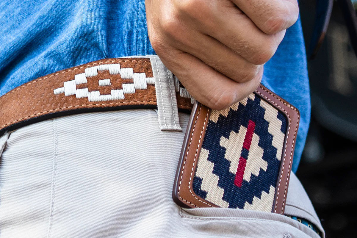 The LA MATERA - TRUCHA Woven and Leather Card Wallet by LA MATERA features brown Argentine leather trim and a woven center with a minimalist geometric navy, cream, and red stripe pattern.