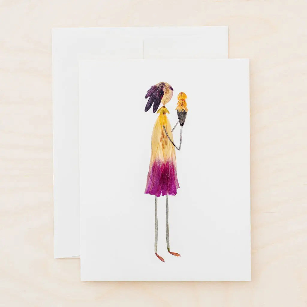 The PETAL PEOPLE PRESS - THREE SCOOPS card by PETAL PEOPLE PRESS showcases a woman holding an ice cream cone made from real pressed flower petals and leaves, displayed on a white surface with green leaves, pruning shears, and a paperclip nearby.