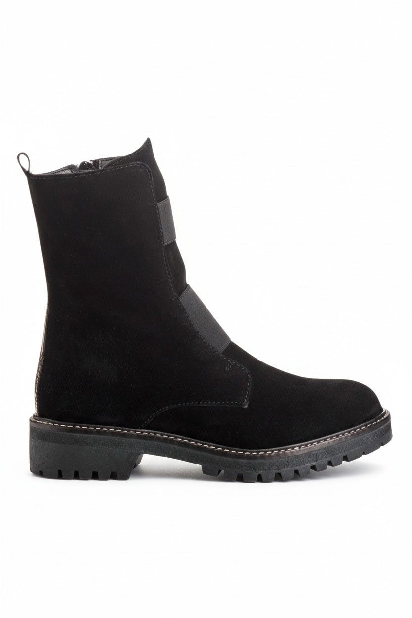The REQINS - DUSKY SUEDE ANKLE BOOT IN NOIR features black suede leather, chunky cleated rubber soles, elastic panels on the front, and side zippers, and is displayed on a light background.
