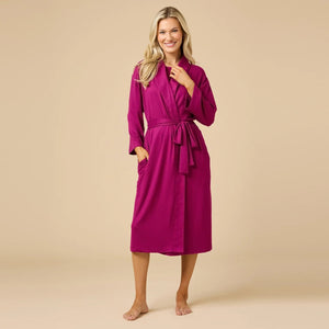 A woman wears a SOFTIES - DREAM SHAWL COLLAR ROBE in pink and white stripes, featuring a shawl collar, a tie waist, and three-quarter length sleeves.