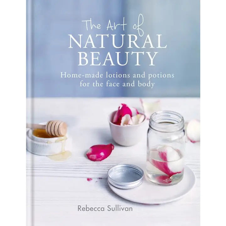 Book cover of &quot;ART OF NATURAL BEAUTY: HOME MADE LOTIONS AND POTION&quot; by MICROCOSM PUBLISHING &amp; DISTRIBUTION features all-natural elements—water and rose petals in a jar, a honey dipper, and bowl—ideal for homemade lotions.