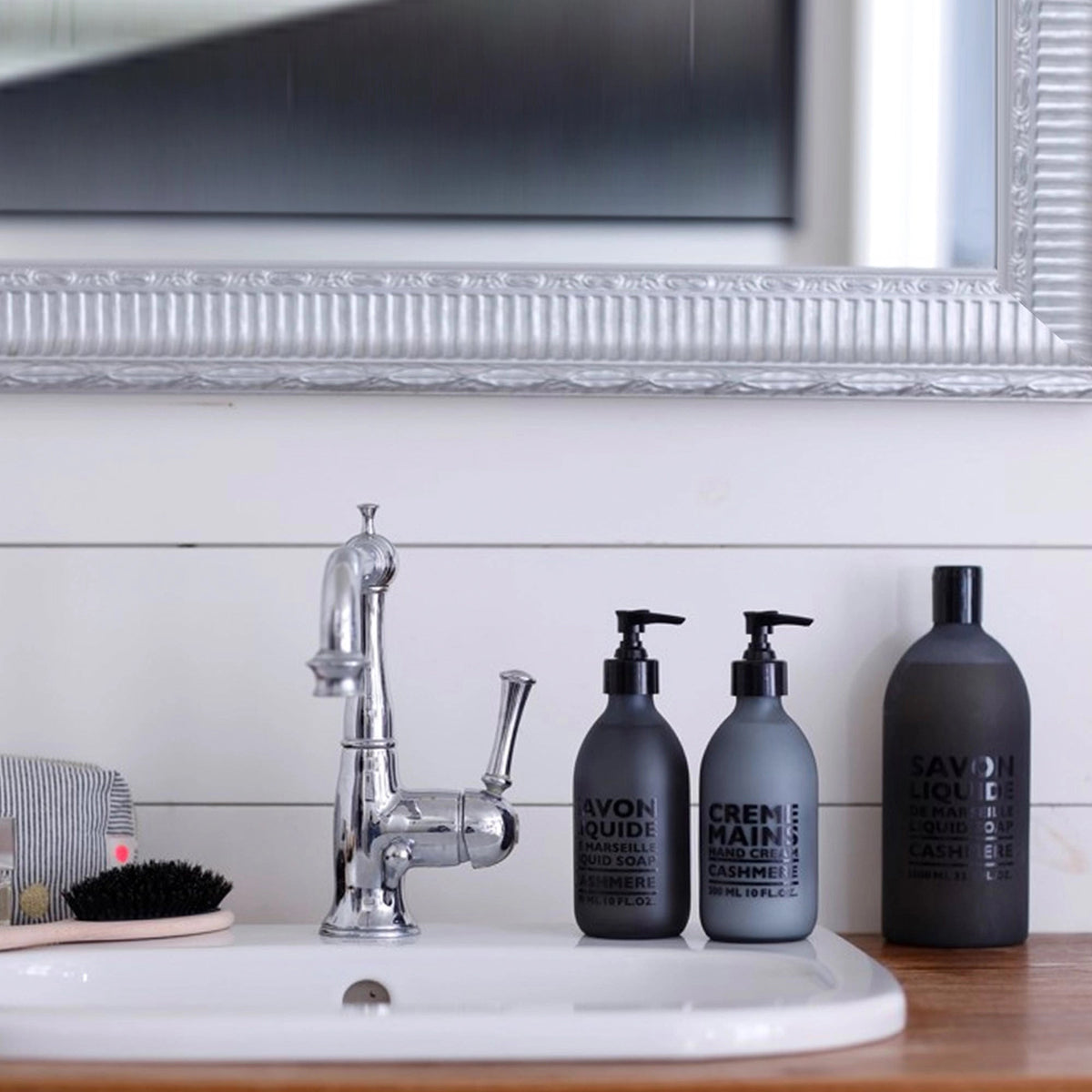 A frosted grey pump bottle of COMPAGNIE DE PROVENCE&#39;s Savon Liquide De Marseille Cashmere Soap by CIE LUXE BRANDS features a black dispenser and contains 300 ml (10 fl. oz.) of soap infused with luxurious botanical oils.