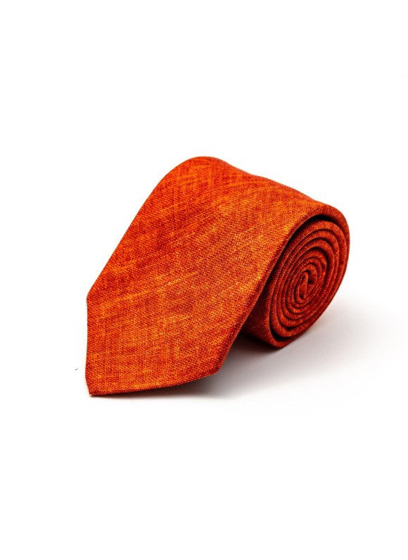 The EDWARD ARMRAH - SOLID RUST SILK TIE by EDWARD ARMAH features a textured silk fabric and is shown rolled up against a white background.