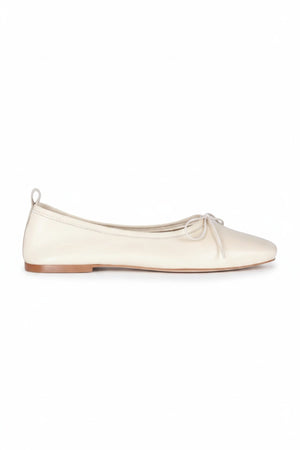 The AUGUSTA - SIENNA BALLET FLAT by AUGUSTA, handcrafted in Spain, showcases a silver finish with a front bow, low brown sole, and heel pull tab, displayed in side profile against a plain light background.