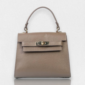 The LE BORSETTE LEATHER SATCHEL BAG is a small, structured satchel-shaped handbag in light pink, featuring a gold clasp at the front. It boasts a single top handle, an adjustable shoulder strap, and two gold-tone hardware pieces on either side of the handle. The textured leather adds to its luxurious and elegant appearance against the plain white background.