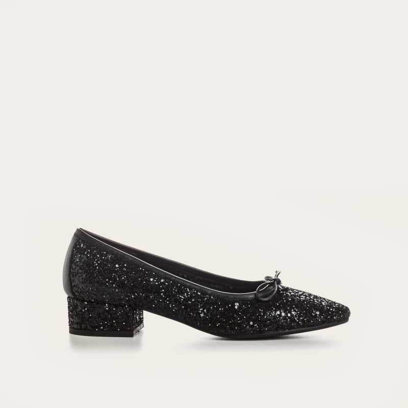 A single REQINS - FETICHE GLITTER HEELED BALLERINA shoe, black and covered in glitter, viewed from above with a small bow on the toe and &quot;REQINS&quot; on the insole—perfect elegant party shoes.