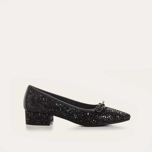 A single REQINS - FETICHE GLITTER HEELED BALLERINA shoe, black and covered in glitter, viewed from above with a small bow on the toe and "REQINS" on the insole—perfect elegant party shoes.