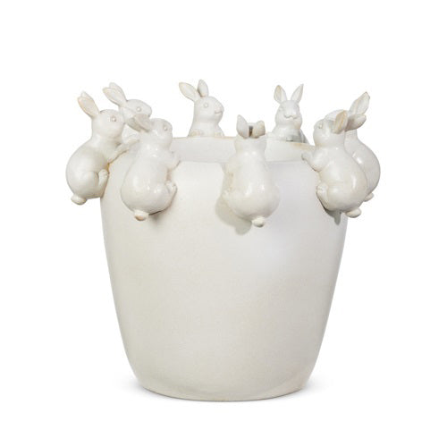 The BUNNY PLANTER by RAZ IMPORTS is a charming white ceramic vase for home decor, featuring rims adorned with small, sculpted bunnies playfully perched on the edge.