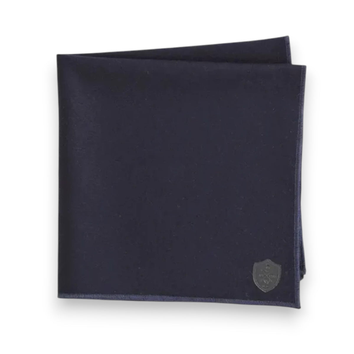 The CLIFTON WILSON - CASHMERE POCKET SQUARE features dark navy blue cashmere with a small silver embroidered crest in one corner, displayed on a white background.