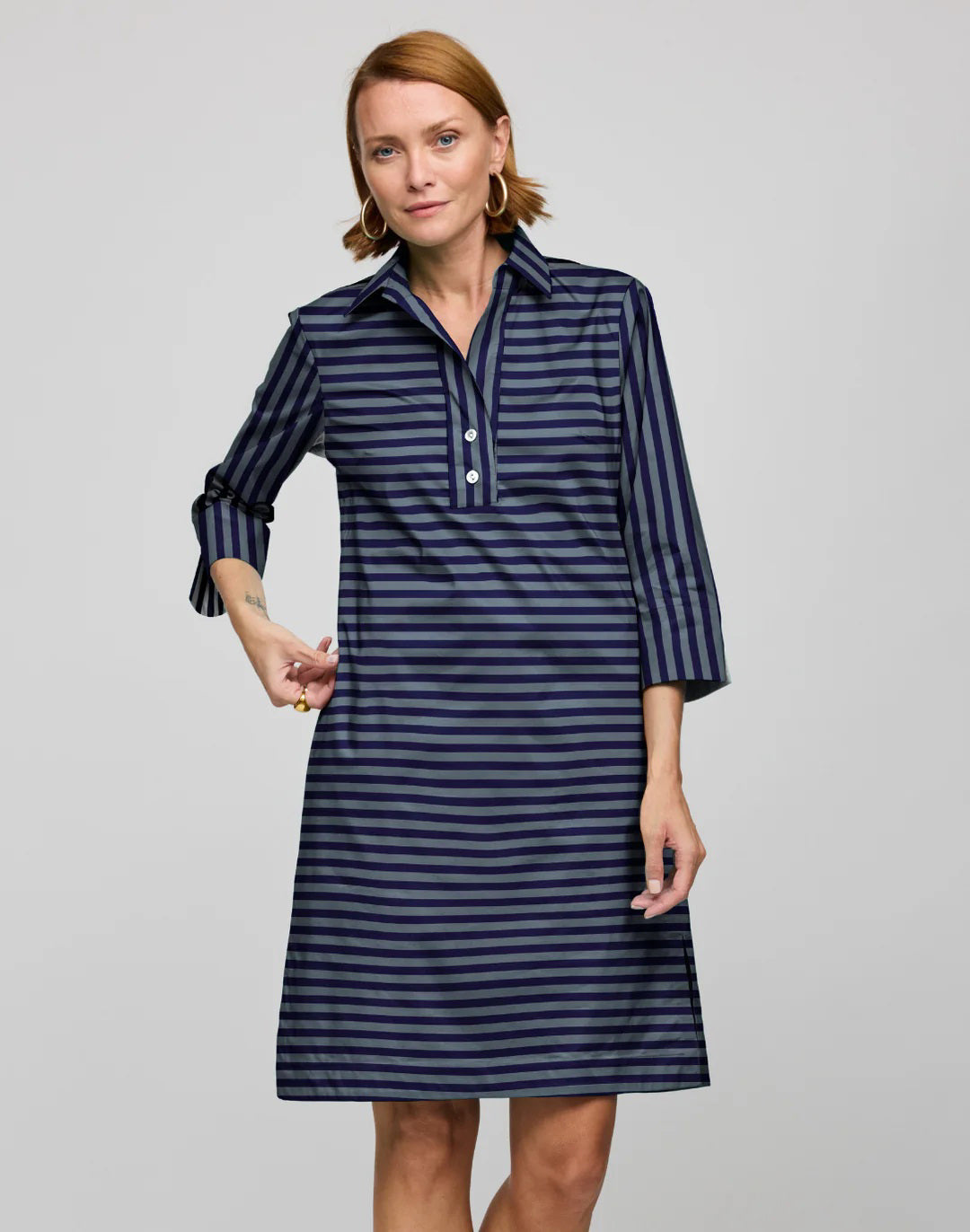 A woman with short light brown hair models the HINSON WU CHARLOTTE 3/4 Sleeve Dress in French Grey/Midnight, featuring cotton fabric, a collar, and three front buttons, standing against a plain gray background.