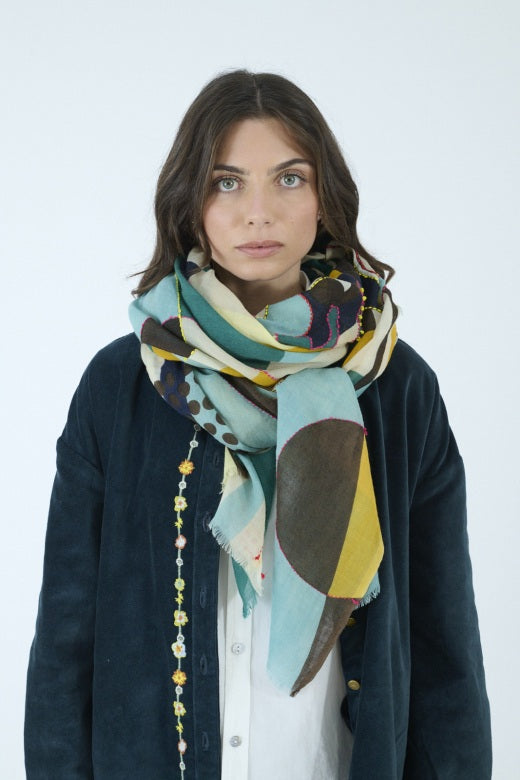 Introducing the STORIATIPIC - BAO Wool Scarf with Embroidery in Blue by STORIATIPIC: a generously sized (100 x 200 cm) wool scarf featuring a modern geometric pattern in teal, mustard yellow, brown, black, and white. Adorned with embroidered circles, dots, and rectangular motifs for a soft texture, this lightweight accessory is finished with frayed edges for added style.