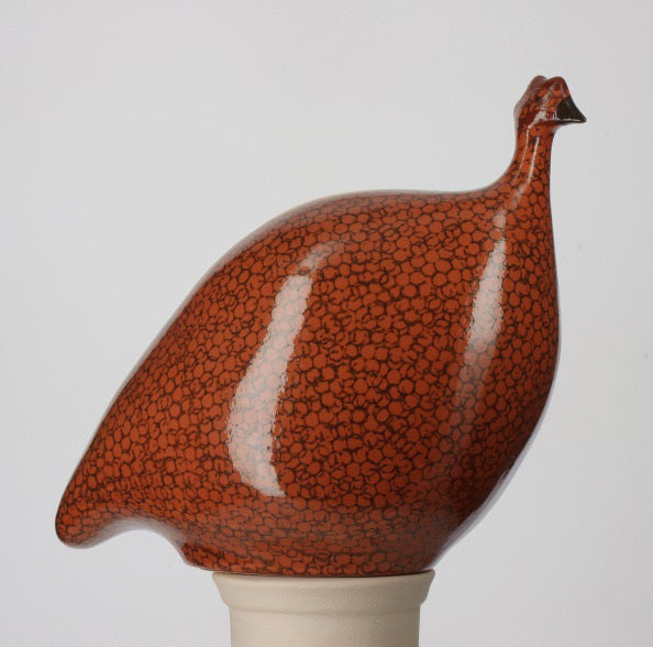 The LES CERAMIQUES DE LUSSAN Large Ceramic French Guinea features a glossy, rounded terracotta bird with red and black spots, perched on a white base, inspired by Heidi Caillard pottery.
