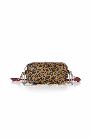 The CRAIE STUDIO - NUAGE LEO SEPIA MINI BAG, featuring a leopard print design, gold zipper, and an extended red strap, is showcased on a white pedestal against a simple backdrop.