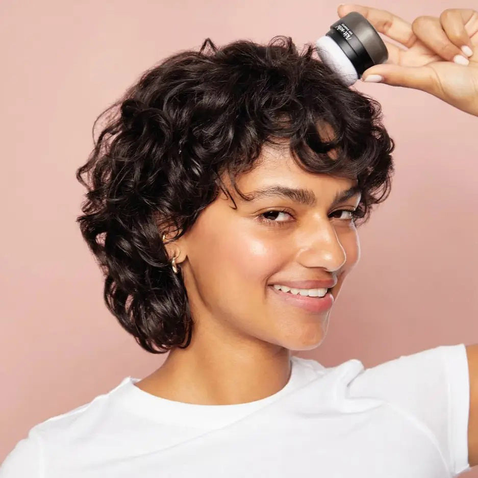 A small, round black container with a matte gray cap labeled "KITSCH Volumizing Rice Protein Dry Shampoo - Dark Tinted" rests on a light gray background—ideal for absorbing oil and refreshing dark hair.