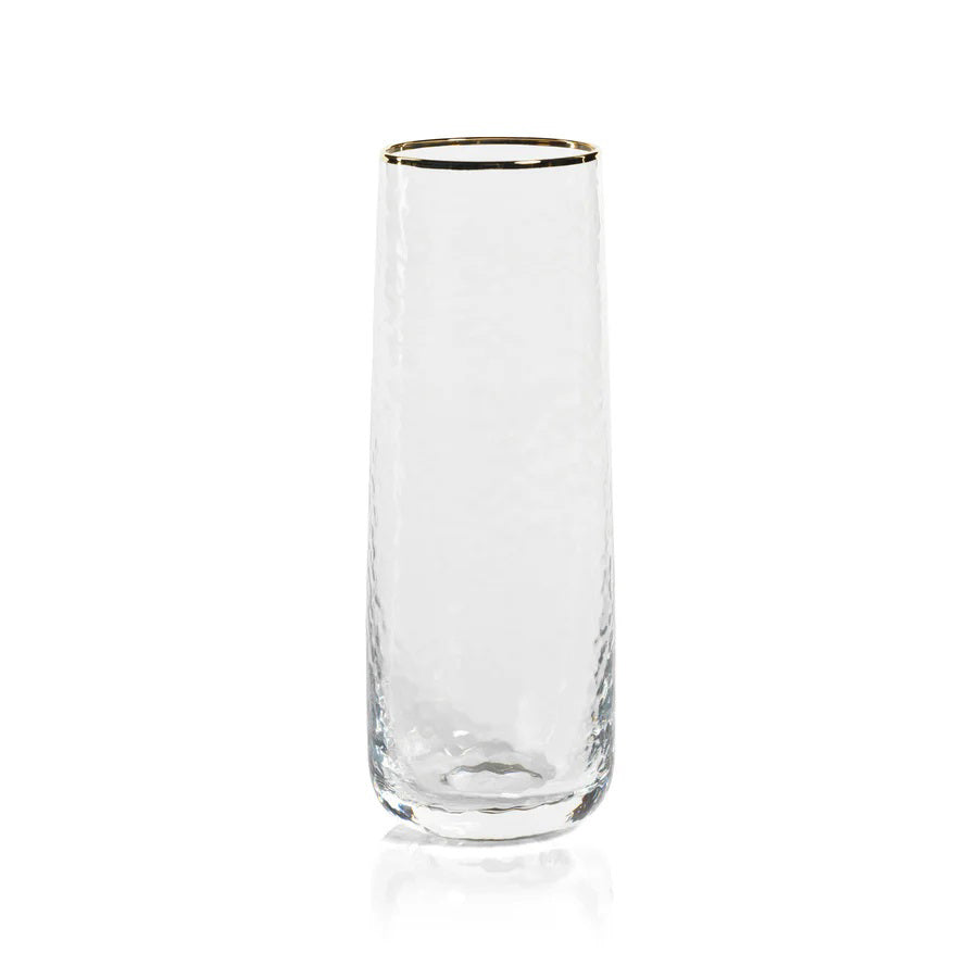A sophisticated, clear Negroni Hammered Stemless Flute from the brand Zodax, featuring a subtly textured design and a delicate gold rim at the top, elegantly displayed upright against a white background.
