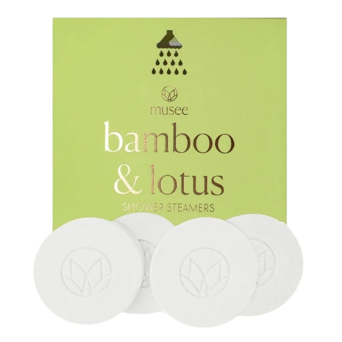 A green box labeled “MUSEE - BAMBOO &amp; LOTUS SHOWER STEAMERS” is displayed, featuring four white round steamers embossed with a leaf design in front. The brand name “MUSEE” appears above the product name, highlighting these natural shower steamers crafted to deliver a spa-like experience.