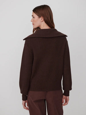 A person wearing a dark brown VARLEY - ENRICO ZIP-THROUGH KNIT JACKET featuring a ribbed soft viscose knit, a high collar, and a front zipper, ideal for cool weather layering.