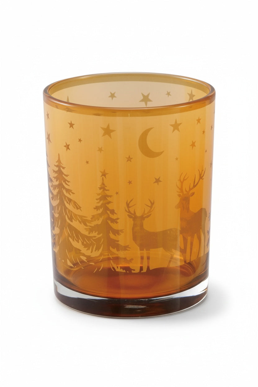 Amber GLASS TEALIGHT/VOTIVE HOLDER WITH LASER ETCHED DEER featuring a woodland deer design with pine trees, stars, and a crescent moon.