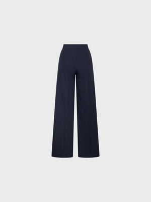 SANDRO FERRONE - PINSTRIPE TROUSER: High-waisted, wide-leg tailored pants with subtle vertical stripes, front pleats, side pockets, and a button closure by SANDRO FERRONE, shown on a plain light gray background.