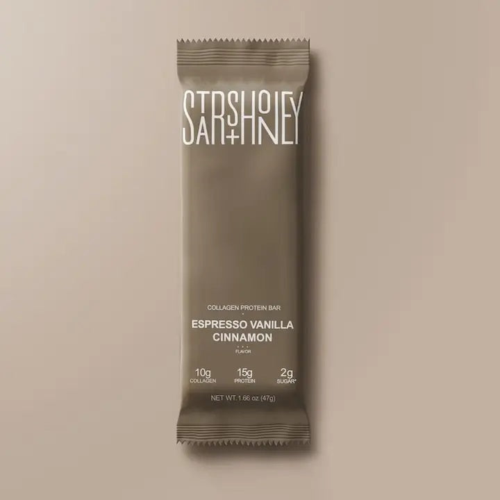 A STARS+HONEY-ESPRESSO VANILLA CINNAMON protein bar by STARS+HONEY rests on a beige surface. The packaging highlights 10g collagen, 15g protein, and just 2g sugar. Ideal for those looking for an espresso-inspired protein bar with extra benefits, its net weight is 1.66 oz (47g).