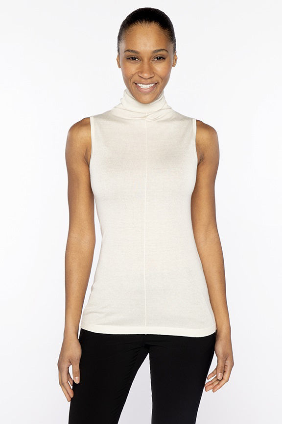 A woman smiles against a plain white background, wearing the KINROSS CASHMERE Seamed Funnel Neck Sleeveless Top by KINROSS, paired with black pants.