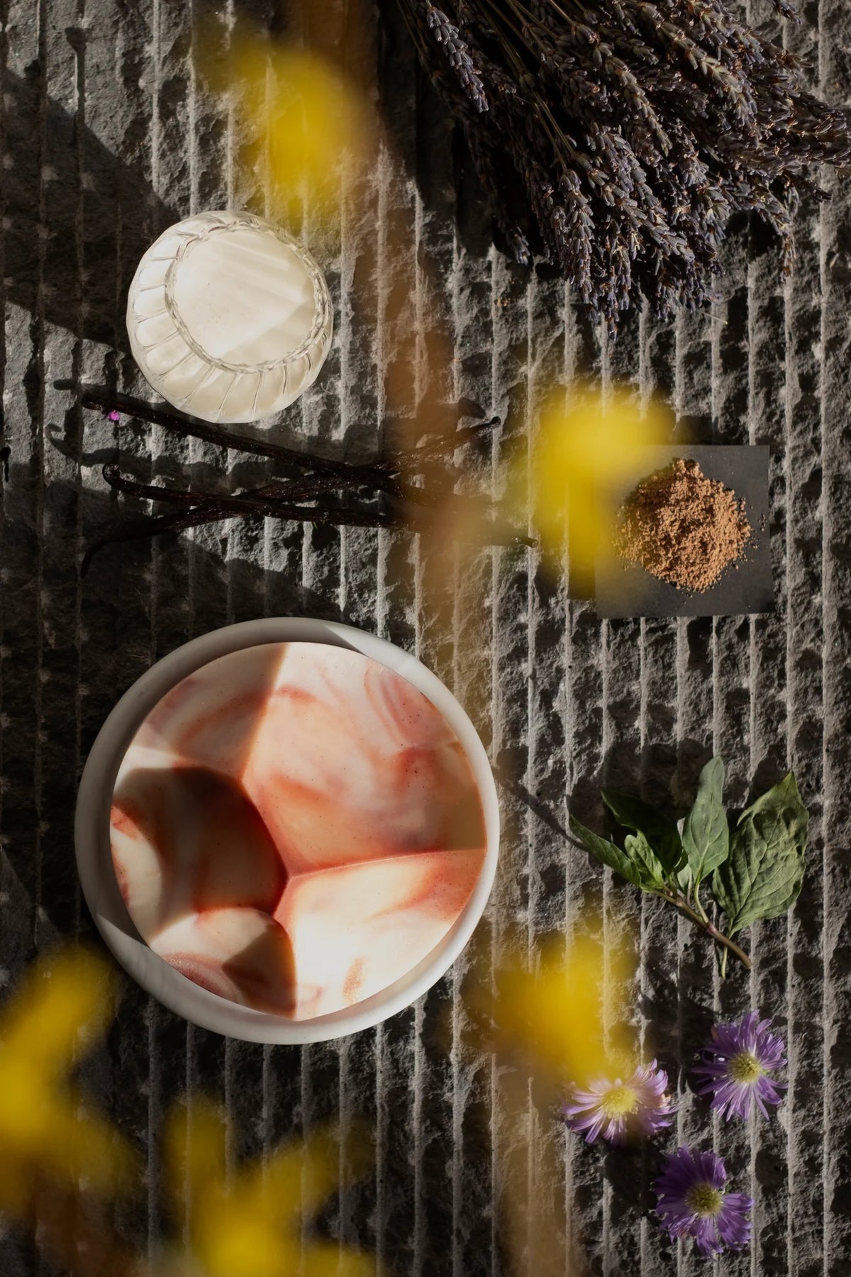The UME STUDIO UME - LAVENDER CREME ERODE SOAP, with white and reddish-brown swirls and sculpted peaks, rests on a round marble-patterned soap dish against a plain background.
