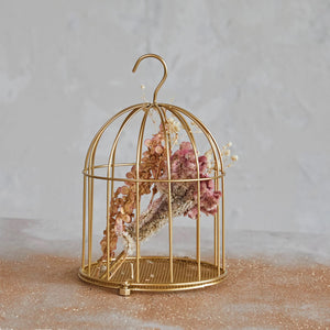 The METAL BIRD CAGE ORN by CREATIVE COOP features a golden finish with vertical bars and a domed top. Designed with a hook for hanging and a small latch-door at the bottom front, this elegant ornament stands gracefully on its base against a plain white backdrop.