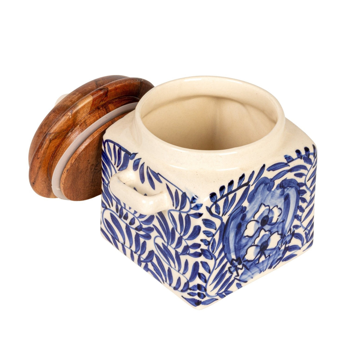 A close-up of the CREATIVE COOP HAND-PAINTED STONEWARE CANISTER WITH LID AND SPOON shows blue floral designs on cream stoneware and an acacia wood lid—an elegant farmhouse kitchen accent.