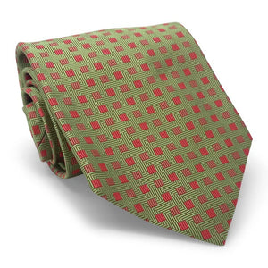 The PETER-BLAIR Bespoke Small Squares Silk Tie in Green by BIRD DOG BAY features a geometric red square pattern and is handmade in New York, shown rolled up on a white surface.