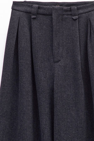 A person is shown from the shoulders down against a plain white background, wearing ELEH - BLACK PALAZZO TROUSERS by ELEH styled with black shoes and a loose-fitting, long-sleeve top.