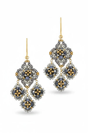 The MIGUEL ASES Crystal Miyuki Chandelier Earrings by MIGUEL ASES, INC. feature intricate beaded designs in silver, gold, and black, with metallic hues forming diamond-shaped patterns for a dazzling effect.