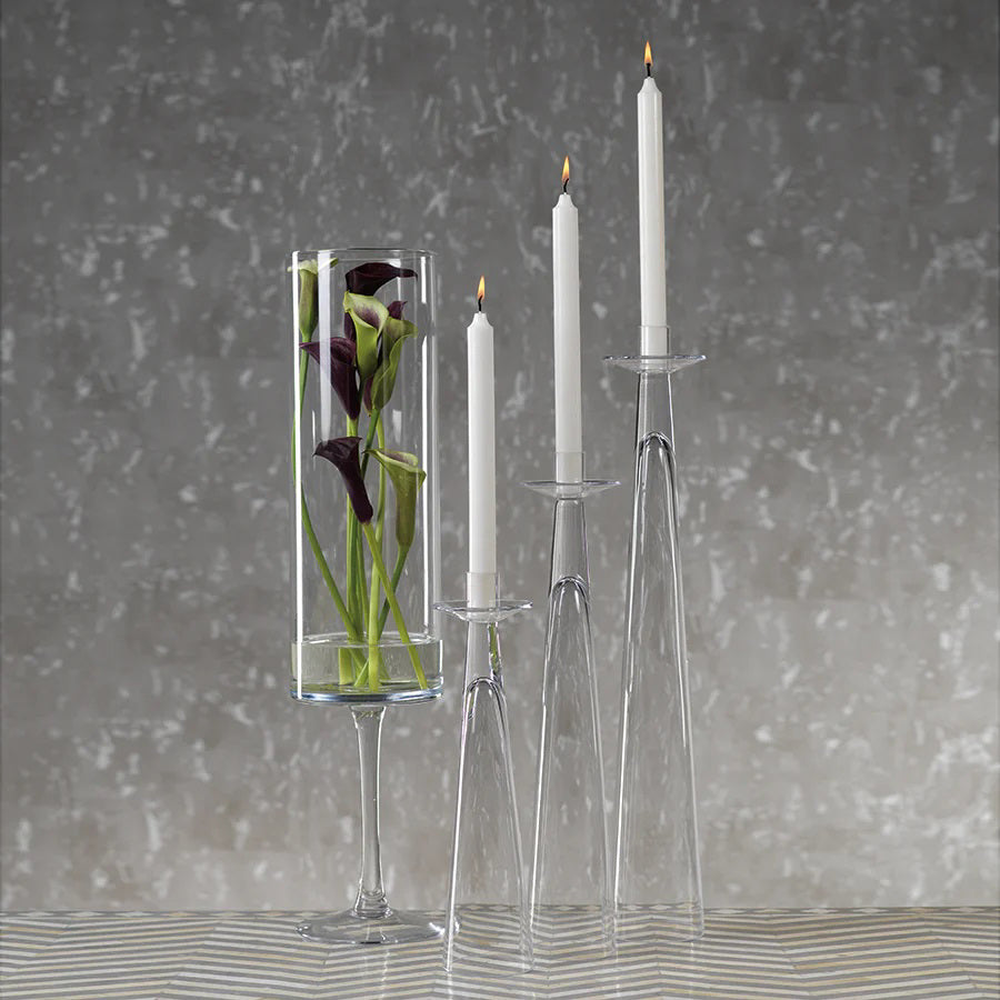 The ZODAX AMIN GLASS CANDLEHOLDER MEDIUM is a tall, clear glass holder with a sleek modern design, narrow base widening upwards, and a small top platform. Dimensions: 3.5 in x 15.75 in (8.89 cm x 40.01 cm).