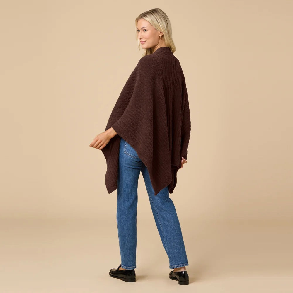 A woman wearing a black SOFTIES - SOLID RIB MARSHMALLOW SHAWL over a grey top and white trousers.
