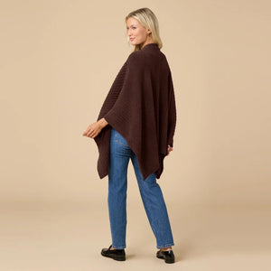 A woman wearing a black SOFTIES - SOLID RIB MARSHMALLOW SHAWL over a grey top and white trousers.