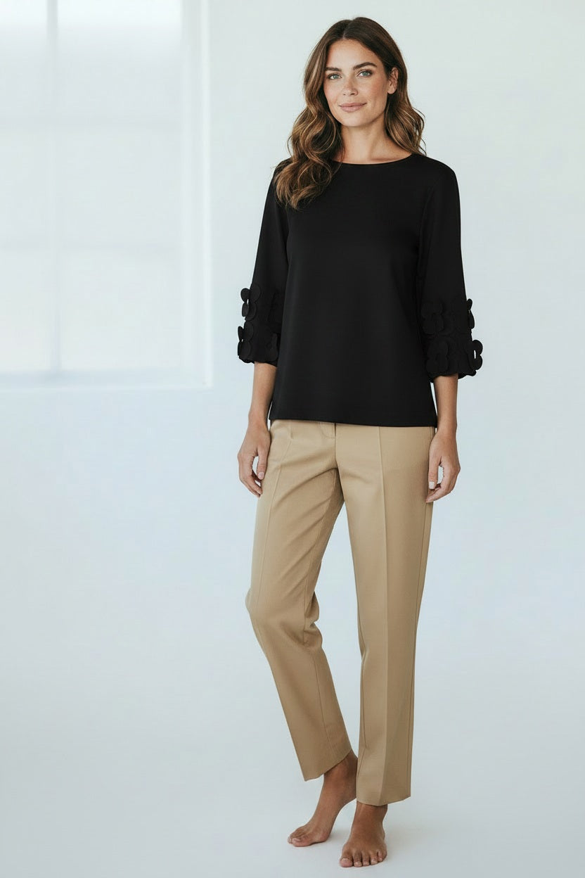 A person wears the MEIMEIJ 3/4 Sleeve Back To Front Top with Lasercut Flower Detail in teal and beige pants, standing against a plain white background.